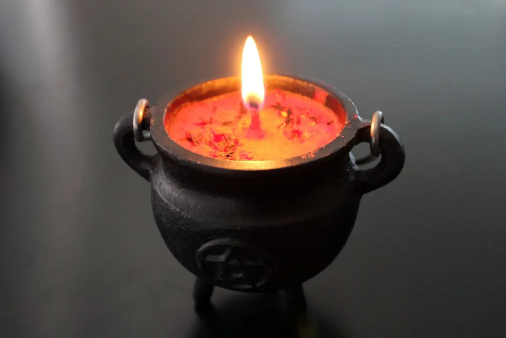 Lit candle in a dark container