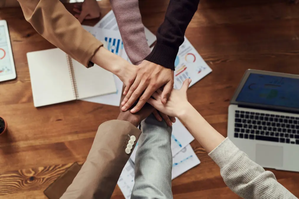 Équipe professionnelle réunissant ses mains au bureau