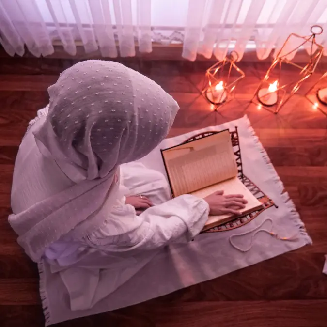 Woman reading the Quran in a prayer space