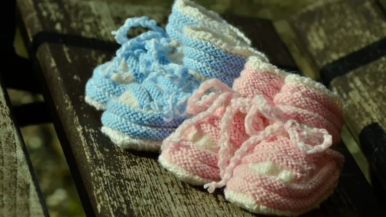 Chaussons de bébé rose et bleu posés sur un banc