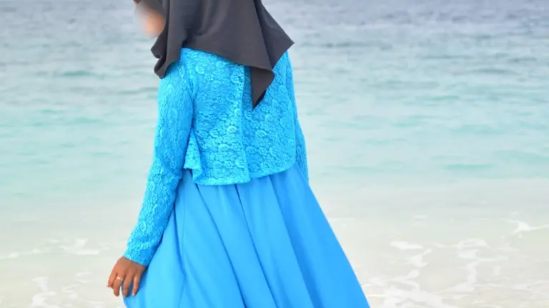 Femme portant une abaya bleue près de la mer