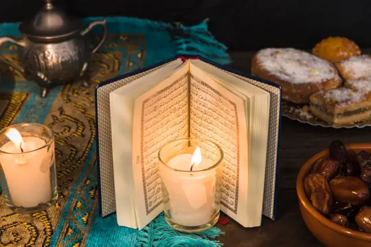 Open Quran with candle and dates