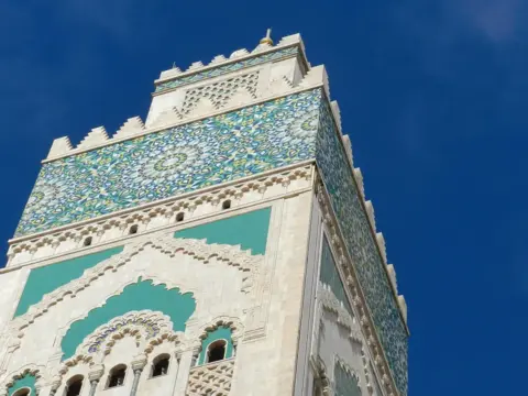 Mosaic-covered minaret under a blue sky