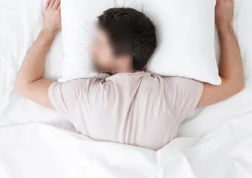 Person sleeping on their stomach in bed