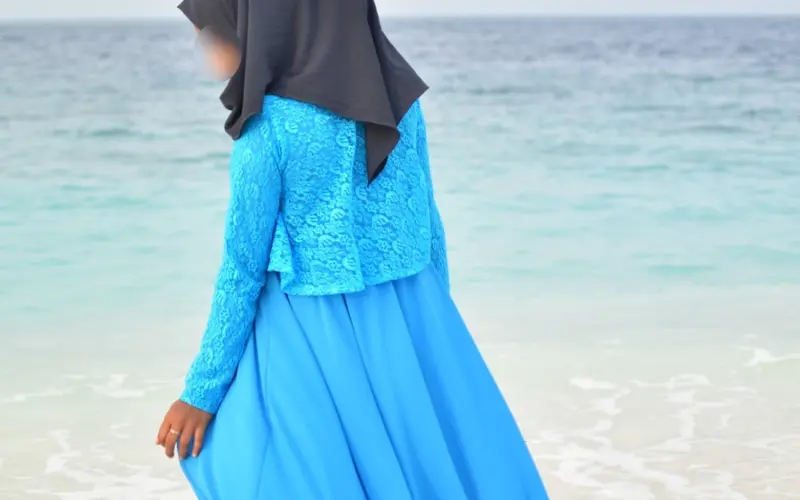 Woman wearing a blue abaya by the sea