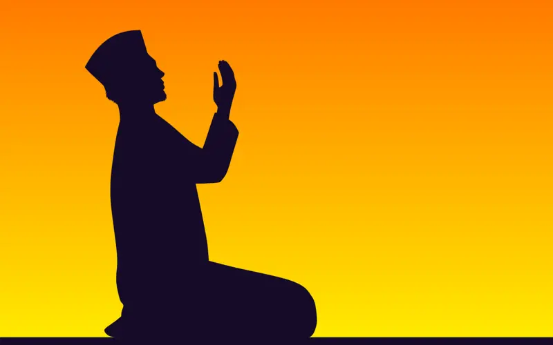 Silhouette of a Muslim praying with raised hands