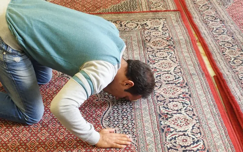 Man prostrating in prayer on a prayer rug