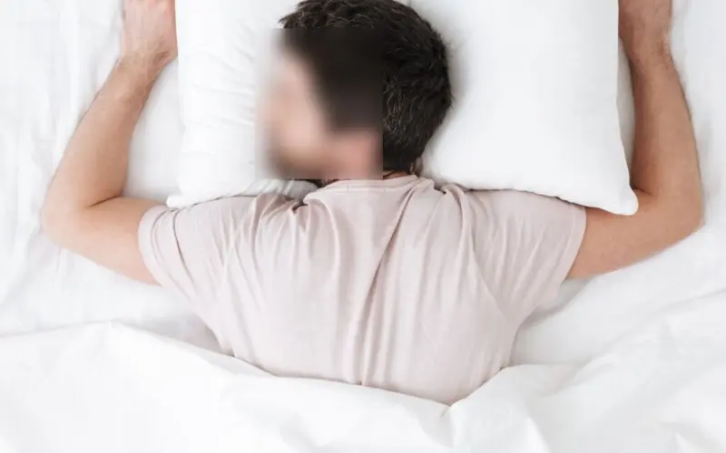 Person sleeping on their stomach in bed