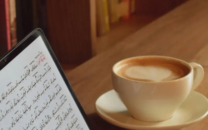 Étudiant apprenant l’arabe en ligne avec une tablette numérique et une tasse de café