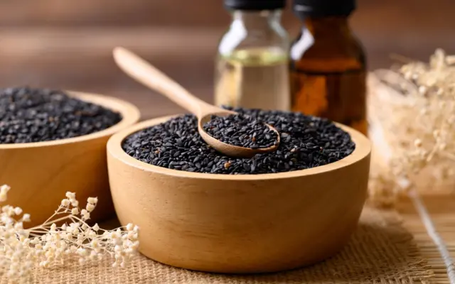 Graines de cumin noir avec huile sur une table