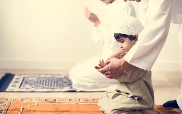 Enfant apprenant la prière avec son père