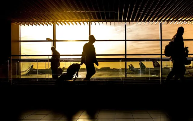 Reisende auf einem Flughafen bei Sonnenuntergang