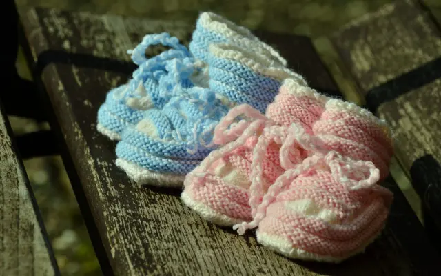Chaussons de bébé rose et bleu posés sur un banc