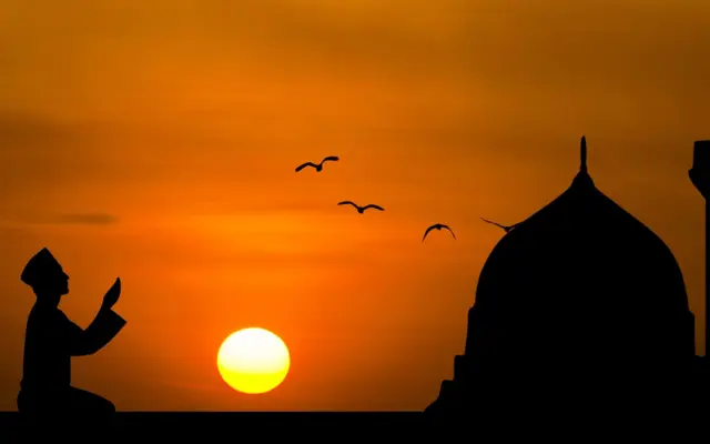 Silhouette eines Mannes beim Duʿā bei Sonnenuntergang