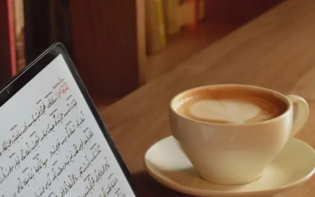 Student lernt online Arabisch mit einem Tablet und einer Tasse Kaffee