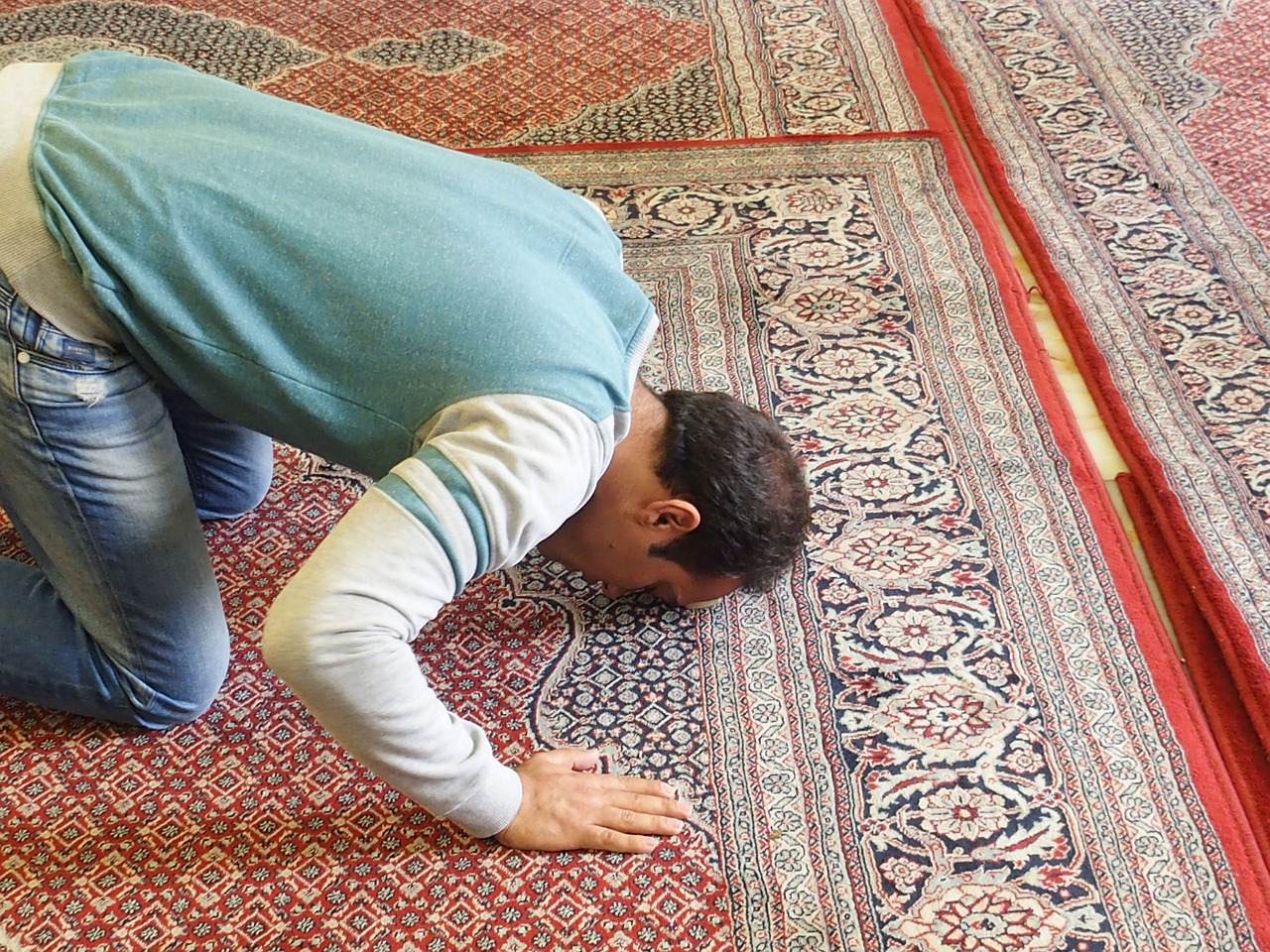 Man prostrating in prayer on a prayer rug