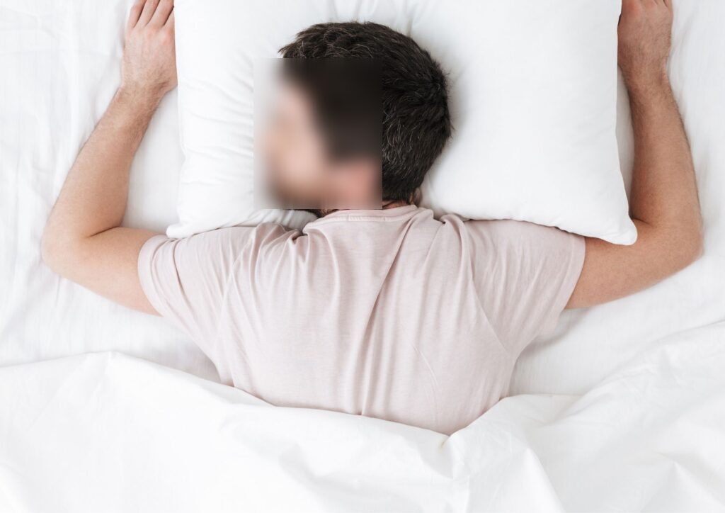 Person sleeping on their stomach in bed